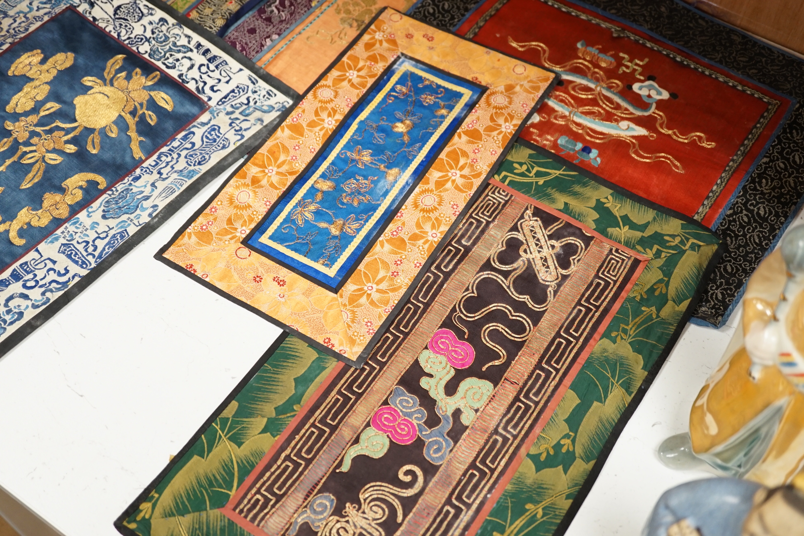 Nine Chinese silk embroidered panels, embroidered with gold thread and bordered with silk damask and brocade